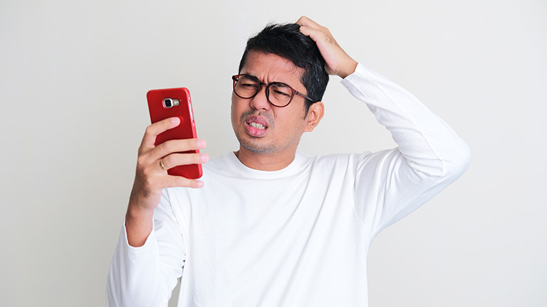 Confused asian man looking at his smartphone